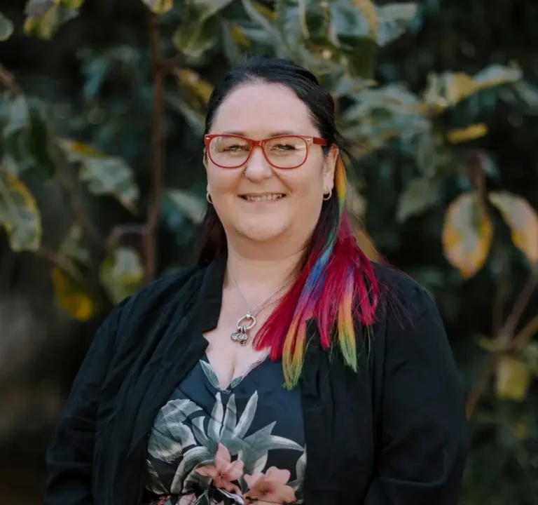 Carina Beattie standing in front of green plant